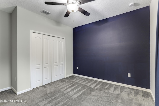 unfurnished bedroom with ceiling fan, a closet, a textured ceiling, and carpet flooring