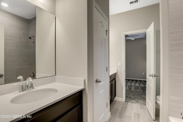 bathroom with vanity, tiled shower, and toilet