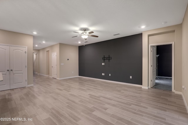 empty room with ceiling fan and light hardwood / wood-style flooring