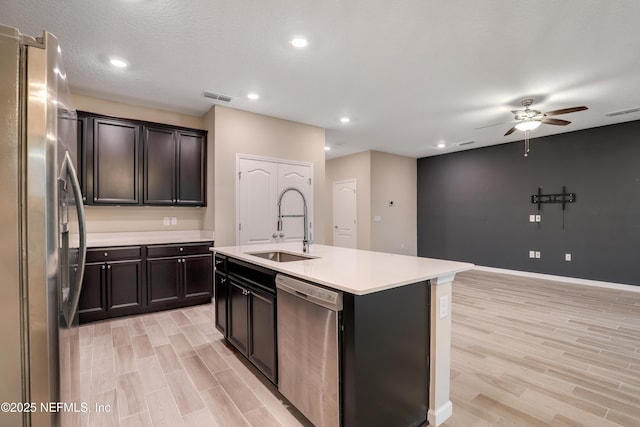 kitchen with an island with sink, sink, ceiling fan, stainless steel appliances, and a textured ceiling