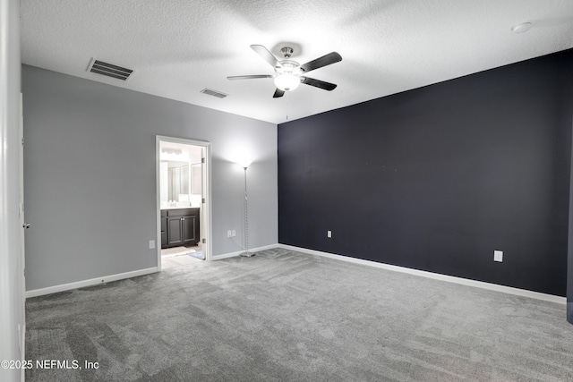 unfurnished bedroom with ceiling fan, carpet flooring, a textured ceiling, and ensuite bath