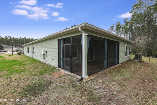 view of property exterior featuring a sunroom, cooling unit, and a lawn