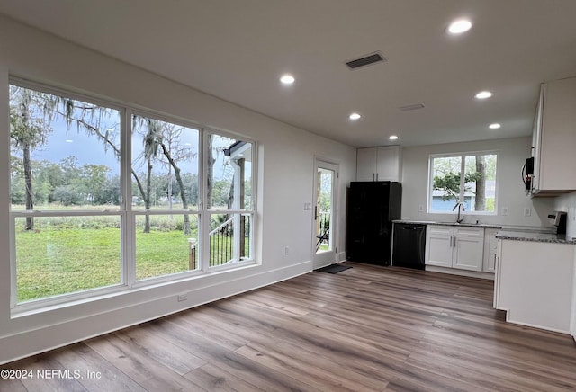 kitchen featuring sink, hardwood / wood-style floors, black appliances, white cabinets, and dark stone counters