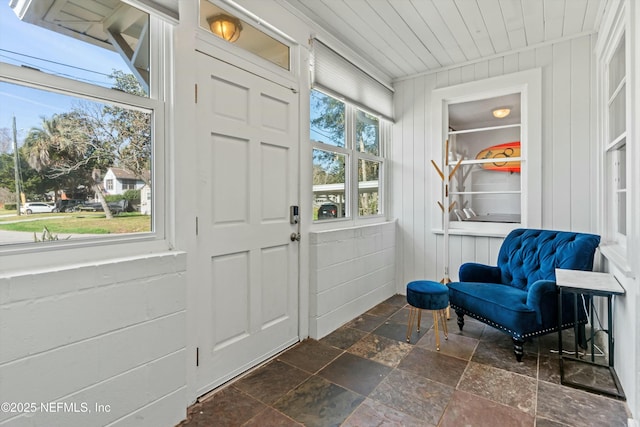 entrance foyer featuring wood ceiling, wooden walls, and a healthy amount of sunlight