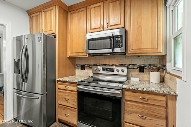 kitchen featuring light stone counters, appliances with stainless steel finishes, and tasteful backsplash