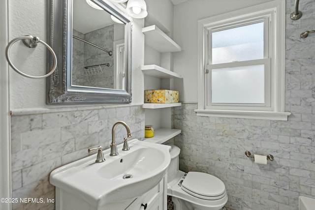 bathroom with vanity, toilet, and tile walls