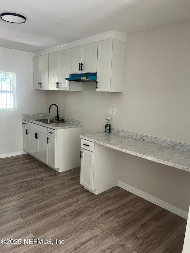 interior space featuring dark wood-style flooring, white cabinetry, a sink, and under cabinet range hood