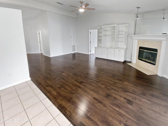 unfurnished living room with light wood-type flooring, vaulted ceiling, ceiling fan, and a fireplace