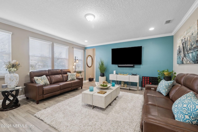 living room with a textured ceiling, visible vents, baseboards, light wood-style floors, and ornamental molding