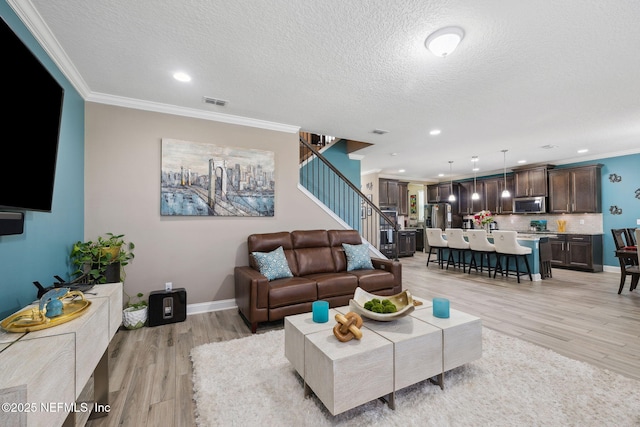 living room featuring ornamental molding, light wood-type flooring, stairway, and baseboards