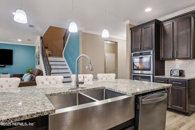 kitchen featuring hanging light fixtures, dark brown cabinetry, double oven, and open floor plan