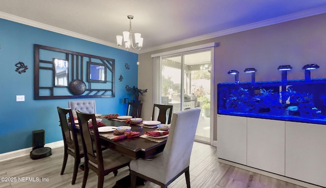 dining space with light wood finished floors, ornamental molding, baseboards, and a notable chandelier