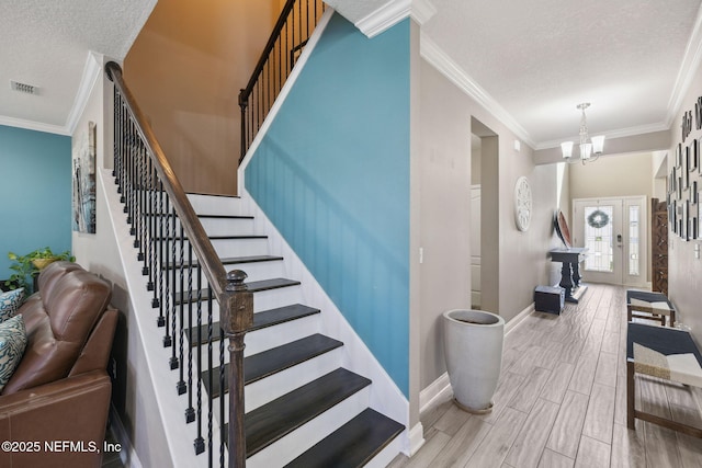 stairs with baseboards, visible vents, ornamental molding, wood tiled floor, and a textured ceiling