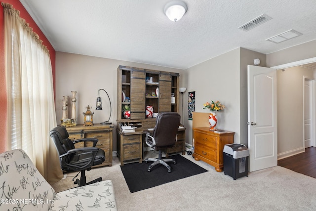 carpeted office featuring visible vents and a textured ceiling