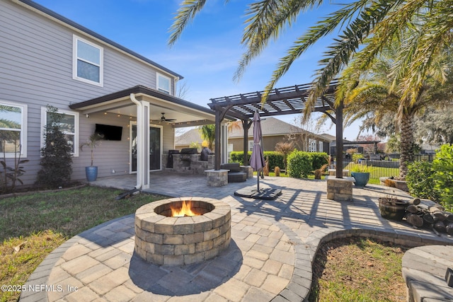 view of patio with area for grilling, a ceiling fan, fence, a pergola, and a fire pit