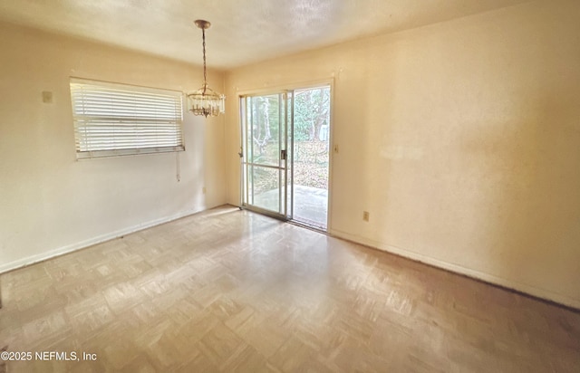 spare room featuring parquet floors and a notable chandelier