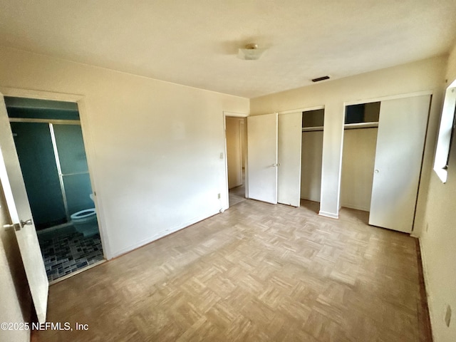 unfurnished bedroom with light parquet floors and multiple closets