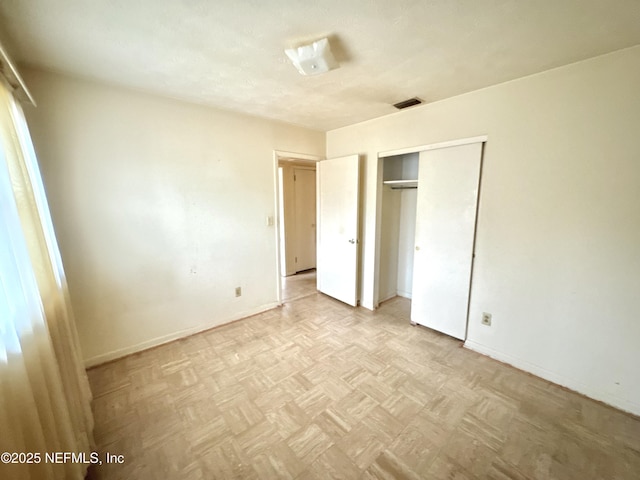 unfurnished bedroom with light parquet flooring and a closet