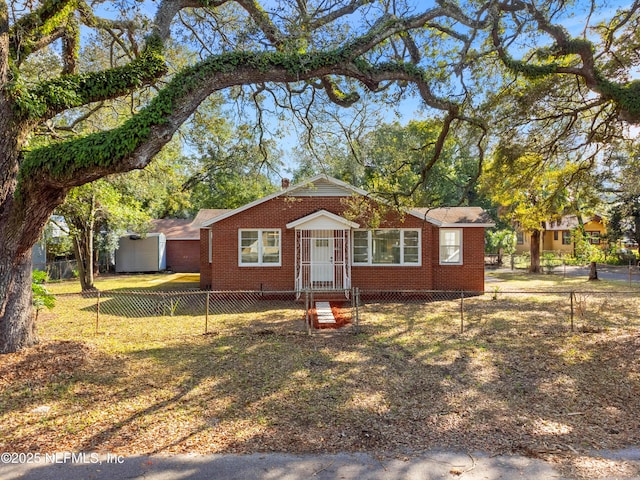 view of front of property featuring a fenced front yard, a front lawn, and brick siding