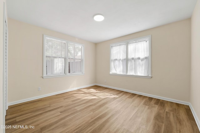 unfurnished room featuring baseboards and light wood finished floors