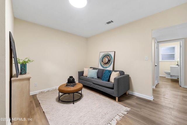 living area featuring baseboards, visible vents, and wood finished floors