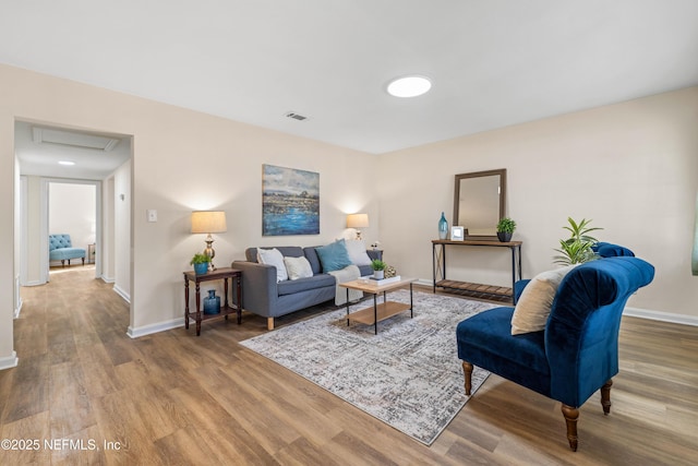 living area featuring baseboards, attic access, visible vents, and wood finished floors