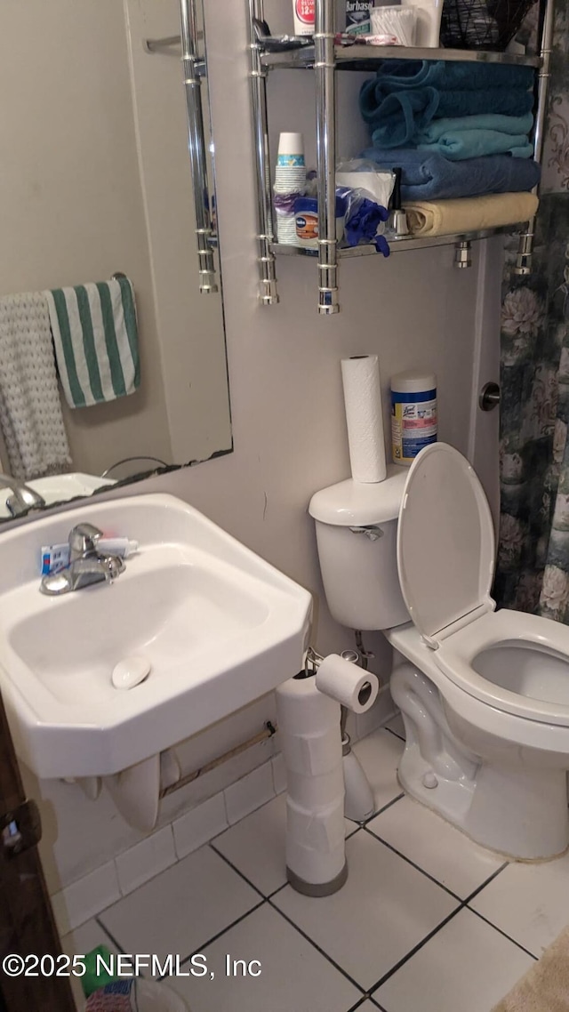 bathroom with toilet, tile patterned flooring, and sink