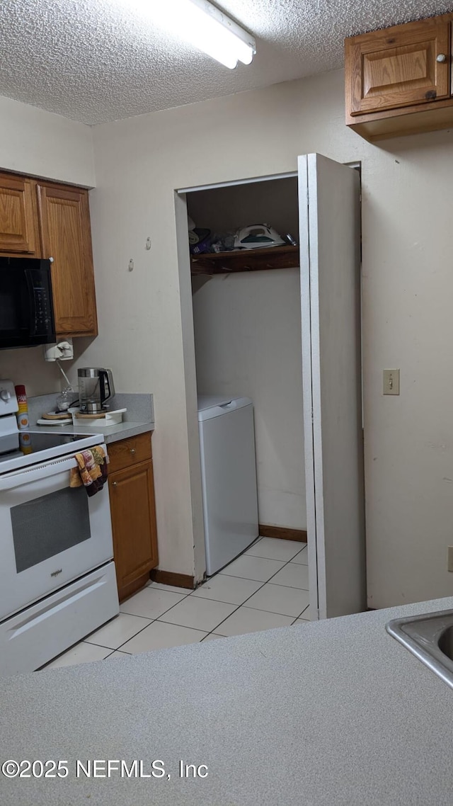 kitchen with refrigerator, light tile patterned floors, a textured ceiling, and electric range