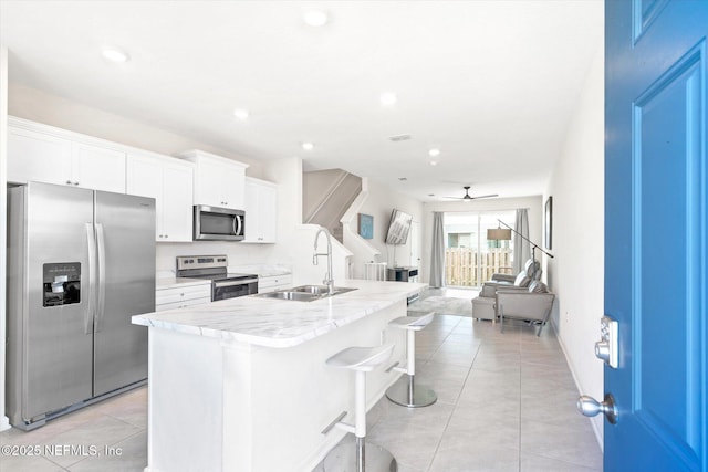 kitchen with an island with sink, sink, white cabinets, a kitchen breakfast bar, and stainless steel appliances