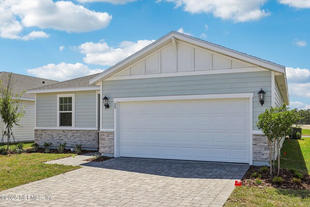 25 Ararat Dr, Palm Coast, FL 32137 - ranch-style house with decorative driveway, stone siding, board and batten siding, and a garage