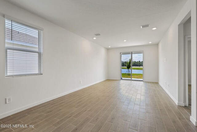 25 Ararat Dr, Palm Coast, FL 32137 - unfurnished room with baseboards, wood finished floors, visible vents, and a water view