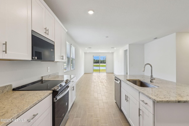 25 Ararat Dr, Palm Coast, FL 32137 - kitchen featuring white cabinets, stainless steel appliances, a sink, light wood-style floors, and light stone countertops