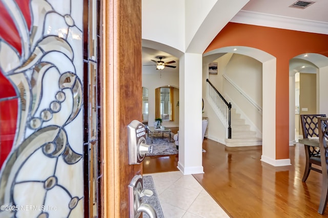 entryway with light tile patterned flooring, ceiling fan, and crown molding