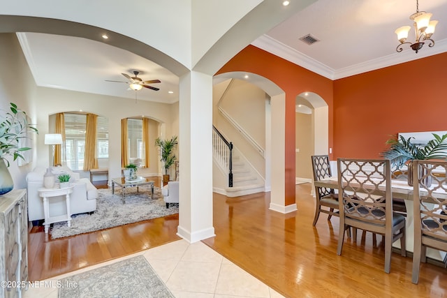 dining space featuring crown molding, ceiling fan with notable chandelier, and light wood-type flooring