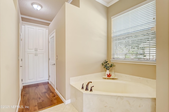 bathroom with ornamental molding, a bath, and a textured ceiling