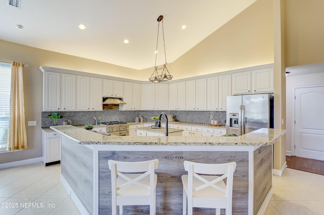 kitchen with light tile patterned flooring, white cabinetry, appliances with stainless steel finishes, pendant lighting, and light stone countertops