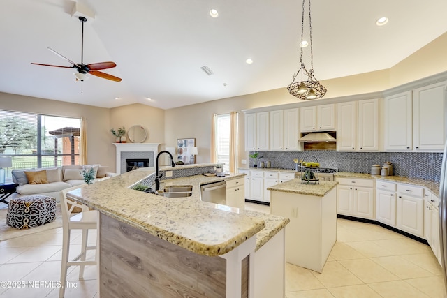 kitchen featuring a breakfast bar area, hanging light fixtures, light tile patterned floors, stainless steel appliances, and a kitchen island with sink