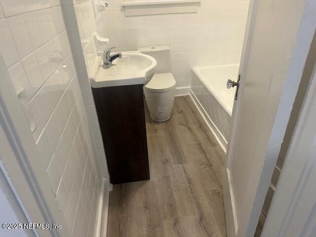 939 Jasmine Pl, Jacksonville, FL 32205 - bathroom with tile walls, a bathtub, hardwood / wood-style flooring, vanity, and toilet
