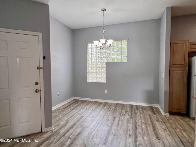 unfurnished dining area featuring a notable chandelier and light hardwood / wood-style flooring