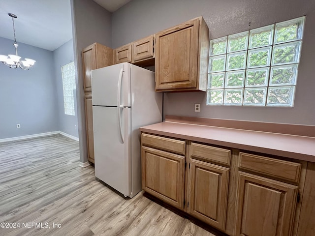 kitchen featuring light wood-type flooring, hanging light fixtures, white fridge, and a notable chandelier