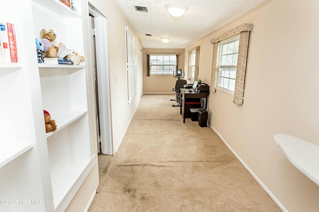 hallway featuring light colored carpet and a textured ceiling