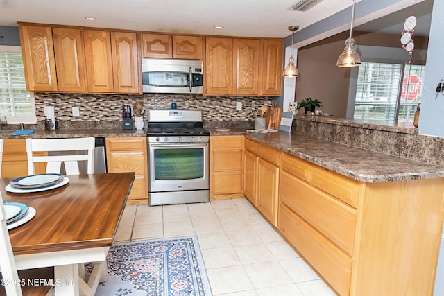 kitchen featuring tasteful backsplash, hanging light fixtures, light tile patterned floors, a wealth of natural light, and stainless steel appliances