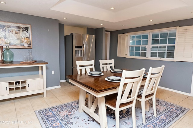 tiled dining area featuring a raised ceiling