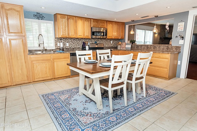 kitchen featuring hanging light fixtures, appliances with stainless steel finishes, sink, and light tile patterned floors