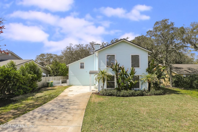 view of front of property featuring driveway, a chimney, a front yard, and fence