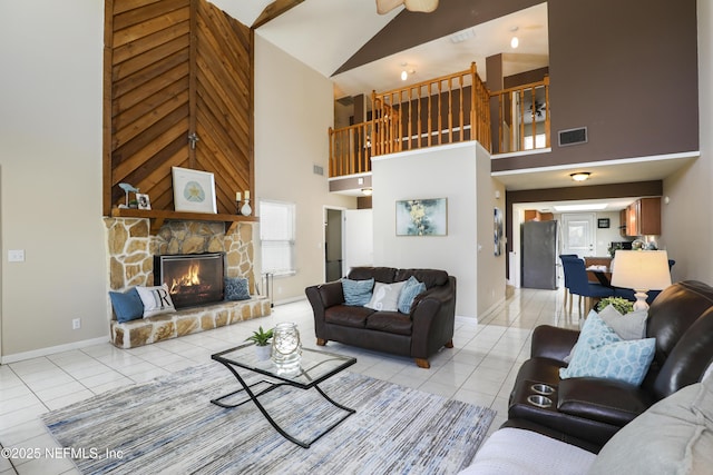 living room featuring light tile patterned flooring, a high ceiling, a fireplace, visible vents, and baseboards