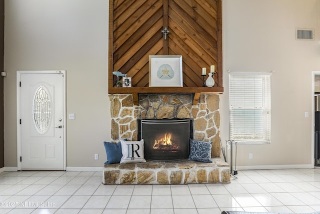 unfurnished living room featuring a fireplace, visible vents, a towering ceiling, tile patterned flooring, and baseboards