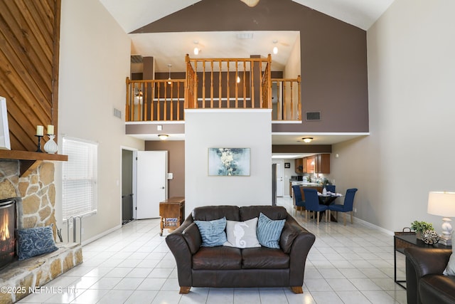 living room with light tile patterned floors, high vaulted ceiling, a stone fireplace, visible vents, and baseboards