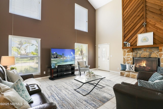 living room with lofted ceiling, a stone fireplace, light tile patterned flooring, and baseboards