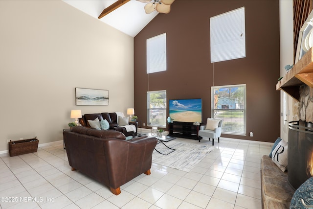 living area with a ceiling fan, high vaulted ceiling, baseboards, and light tile patterned floors